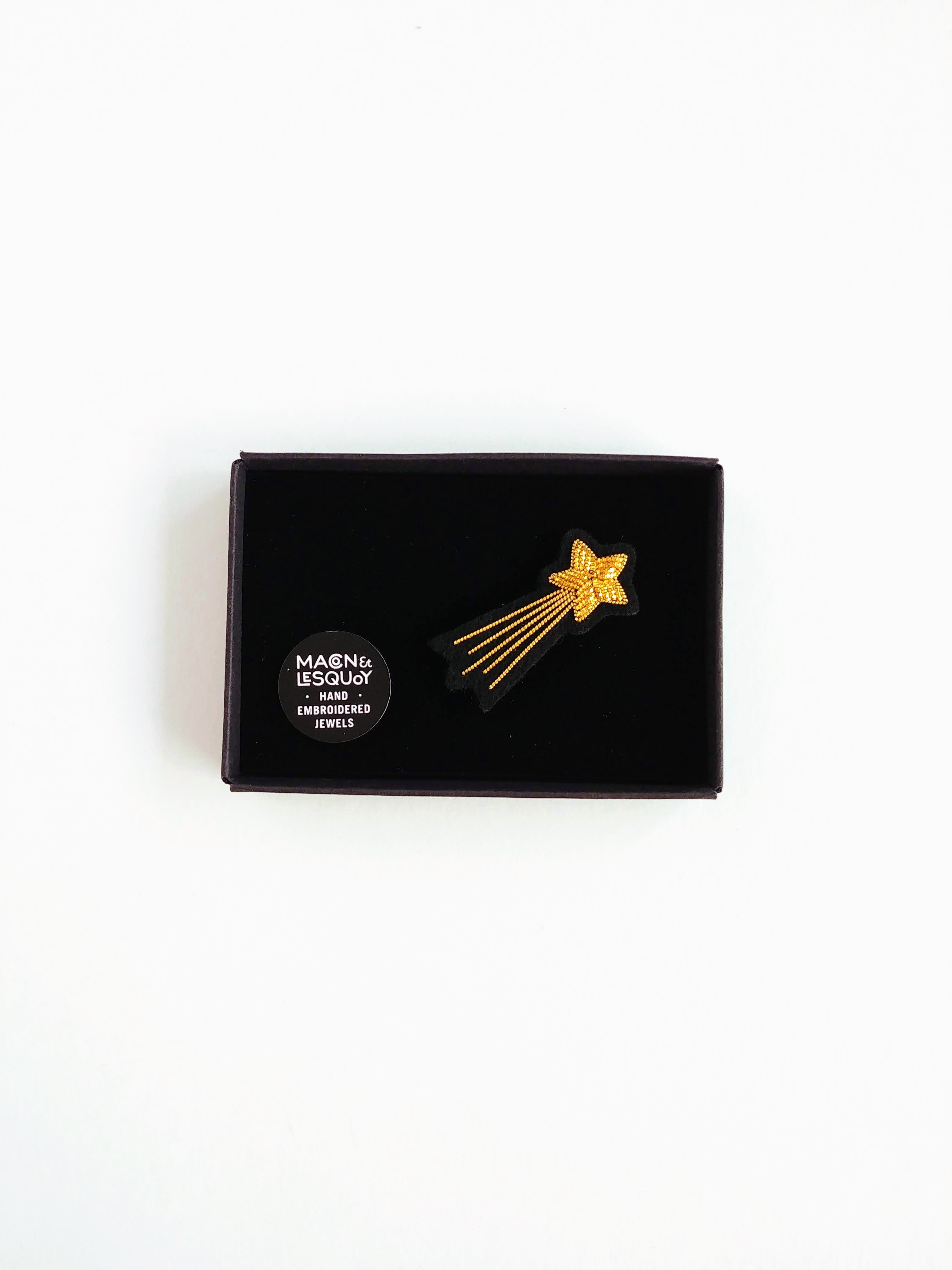 broche brodée en forme d'étoile filante dans une boite noire